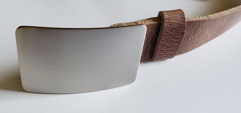 May include: A brown leather belt with a silver metal buckle. The buckle is rectangular and has a smooth, brushed finish.