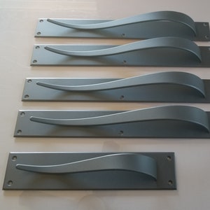 May include: Five grey metal door handles with a curved design. The handles are rectangular and have a brushed finish.