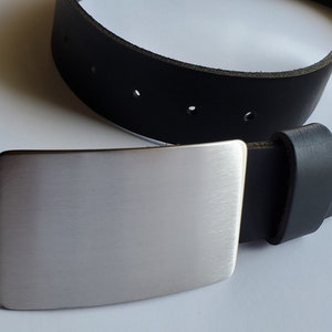 May include: A black leather belt with a silver metal buckle. The buckle is rectangular and has a brushed finish.