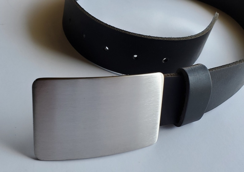 May include: A black leather belt with a silver metal buckle. The buckle is rectangular and has a brushed finish.