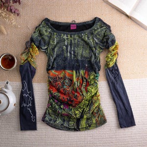 May include: A set of three ceramic mugs with a speckled, cream-colored glaze. Each mug features a different hand-painted floral design in shades of blue, green, and yellow. The mugs have a simple, rounded shape and a comfortable handle.