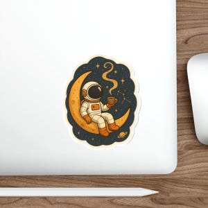 May include: A sticker featuring an astronaut in a white and orange spacesuit, seated on a crescent moon. The astronaut holds a brown mug, with steam rising against a starry night sky background. A small planet is visible below the moon.