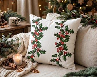 May include: A square throw pillow with a white base featuring two vertical botanical illustrations of green holly leaves and bright red berries. The design is centered on the front of the pillow, which has a smooth, fabric texture.