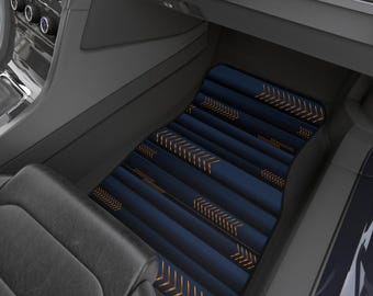 May include: A navy blue car floor mat with a geometric design. The mat features parallel lines with gold arrow accents. The mat is placed in the driver's side footwell of a car, with the car's interior visible in the background.