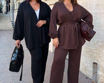 May include: Two matching sets consisting of long-sleeved cardigans and wide-leg trousers. One set is solid black, and the other is solid dark brown. The brown cardigan features a waist tie, and both sets are paired with matching handbags.
