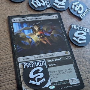 Pode incluir: Uma carta de Magic: The Gathering, "Scheming Silvertongue", com vários tokens "PREPARED" em preto e branco. Os tokens têm um design estilizado de "S" e livro. A carta apresenta uma ilustração de um vampiro bruxo e texto do jogo.