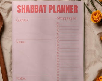 May include: A pink "Shabbat Planner" notebook with the title in bold, red letters. The notebook has sections for guests, menu, and notes, with a shopping list section on the right. Yellow roses and a wooden spoon are in the background.