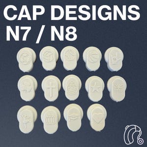 May include: A set of 15 white hearing aid cap designs with various symbols, including a soccer ball, basketball, baseball, crown, shamrock, cross, Easter egg, star, butterfly, ballerina, pumpkin, graduation cap, heart, and a hearing aid.