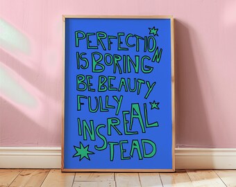 May include: A framed art print with a blue background and green text that reads "PERFECTION IS BORING BE BEAUTY FULLY INSREAL STEAD". The artwork is in a wooden frame and is displayed against a pink wall and wooden floor.