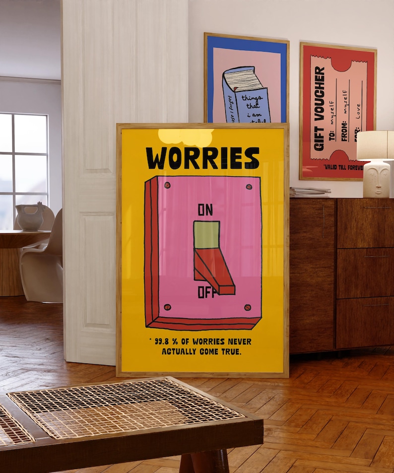 K&ouml;nnte beinhalten: Ein gerahmtes gelbes Poster mit dem Wort "WORRIES" &uuml;ber einer rosa Lichtschalter-Illustration. Der Schalter befindet sich in der Position "OFF". Der Text unten lautet "99,8 % DER SORGEN WERDEN NIE WAHR."