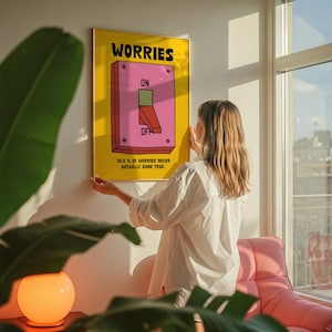 K&ouml;nnte beinhalten: Ein gerahmtes Poster mit gelbem Hintergrund und dem Wort "WORRIES" in fetten schwarzen Buchstaben. Das Poster zeigt einen rosa Schalter mit den Aufschriften "ON" und "OFF". Der Text "99,8% OF WORRIES NEVER ACTUALLY COME TRUE" steht unten.