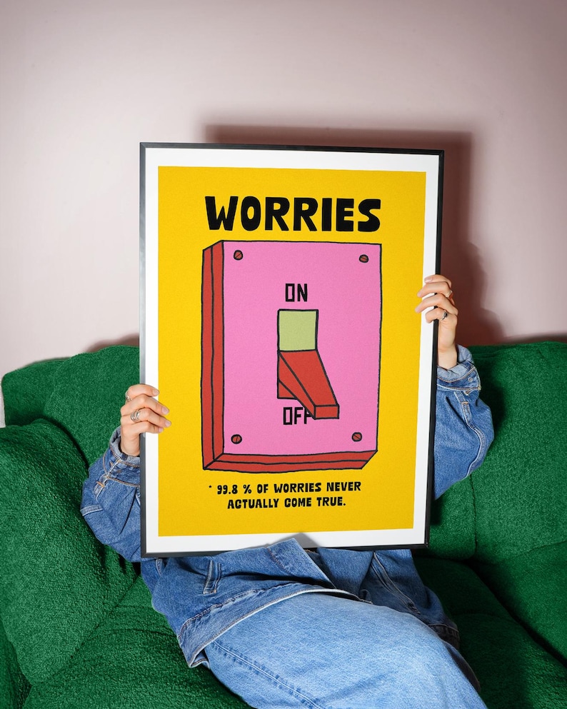 K&ouml;nnte beinhalten: Ein gerahmtes Poster mit gelbem Hintergrund und dem Wort "WORRIES" in Schwarz. Ein rosa Schalter mit "ON" und "OFF" befindet sich in der Mitte. Der Text "99,8% OF WORRIES NEVER ACTUALLY COME TRUE" steht unten.
