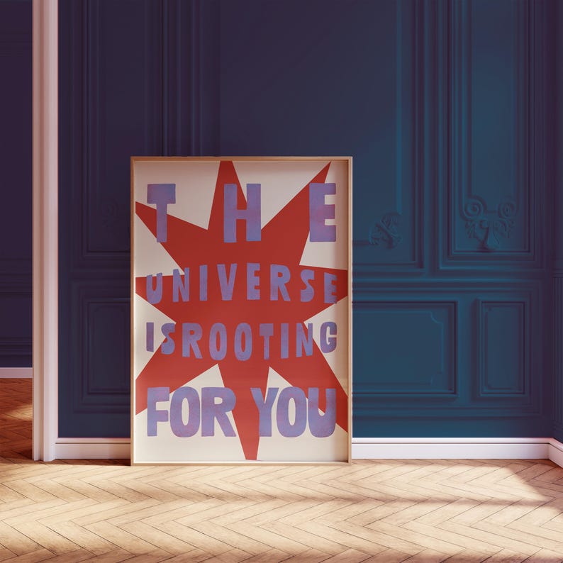 Pode incluir: Um p&ocirc;ster com uma estrela vermelha e texto azul que diz "THE UNIVERSE IS ROOTING FOR YOU".
