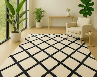 Può includere: Tappeto color crema con motivo a rombi neri. Il tappeto è posato su un pavimento marrone chiaro in una stanza con ampie finestre e diverse piante in vaso. La stanza presenta anche una poltrona beige e un tavolino in legno.