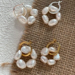 Peut inclure: Deux paires de créoles avec des accents de perles. Une paire est en argent avec des perles blanches, et l'autre paire est en or avec des perles blanches.