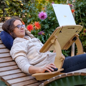 Può includere: Una scrivania in legno per laptop con altezza e angolazione regolabili. Progettata per l'uso reclinato. Il laptop è un modello ASUS bianco. La scrivania è in legno chiaro e ha una piccola piattaforma per un mouse.