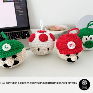 Puede incluir: Cuatro adornos navideños hechos a mano con ganchillo. Los adornos están diseñados para parecerse a personajes de un videojuego popular. Cada adorno tiene un lazo para colgar. Los personajes incluyen un personaje con sombrero verde, un personaje con gorra roja, una seta blanca y un dinosaurio verde.