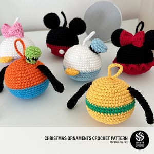 May include: Crochet Christmas ornaments featuring Mickey Mouse, Minnie Mouse, Donald Duck, Goofy, and a yellow ornament with a green stripe. The ornaments are handmade and have a vintage look.