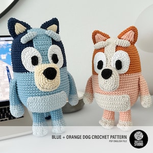 Puede incluir: Dos figuras de perro hechas a mano con ganchillo, una azul y otra naranja, ambas con detalles blancos y negros. Las figuras están sobre una superficie blanca. El texto dice "BLUE + ORANGE DOG CROCHET PATTERN PDF ENGLISH FILE".
