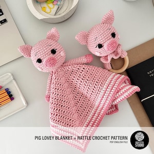 Puede incluir: Manta y sonajero de cerdo de crochet rosa. La manta tiene un borde blanco y el sonajero tiene un anillo de madera. El patrón está disponible para descargar en PDF.