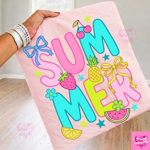 May include: A pink blanket featuring the word "SUMMER" in bright, playful lettering. The design incorporates a blue bow, cherries, a pineapple, a yellow bow, a strawberry, a flower, a watermelon slice, and a lemon slice.