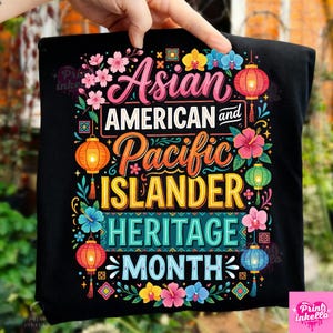 Può includere: T-shirt nero con un design colorato che celebra il Mese del patrimonio asiatico americano e delle isole del Pacifico. Il design include elementi floreali, lanterne e il testo "Asian American and Pacific Islander Heritage Month."