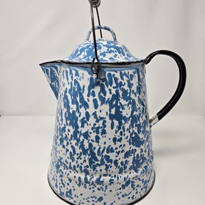 May include: A vintage blue and white speckled enamelware coffee pot with a black handle and a wire bail handle.