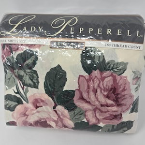 May include: A full sheet set in a clear plastic package. The set features a floral pattern with large pink and mauve roses and green leaves on a cream background. The packaging reads "Lady Pepperell" and "180 Thread Count".