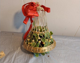 May include: A gold wire bell-shaped Christmas ornament filled with green and white faux holly berries and a red satin bow.