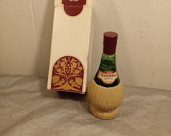 May include: A vintage Avon Chianti Wild Country cologne bottle with its original box. The bottle is shaped like a wine flask, with a brown cap and a woven basket-like design around the base. The box is cream-colored with the Avon Chianti logo.