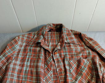 May include: A long-sleeved plaid shirt with a button-up front and a single pocket on the left side. The shirt is red, green, and white.