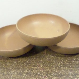 Pode incluir: Três tigelas de cerâmica marrom empilhadas umas sobre as outras.