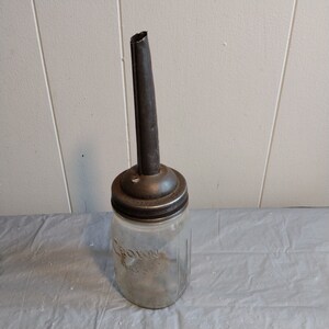 Peut inclure: Un bocal en verre vintage avec un couvercle en métal et un bec verseur. Le bocal est étiqueté "Crown Mason".