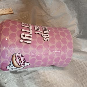 Puede incluir: Un vaso rosa con un patr&oacute;n de corazones y las palabras "pretty things" en blanco. Tambi&eacute;n se muestra un dibujo animado de una rosquilla con glaseado rosa y chispas.