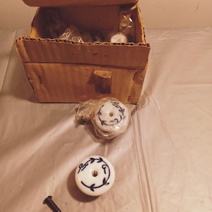 Puede incluir: Una caja de tiradores de cajones de cerámica blanca con diseños florales azules. Los tiradores tienen un solo agujero para tornillos y vienen con un tornillo.