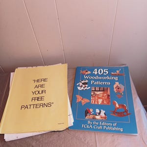 May include: A stack of yellow paper with the text "HERE ARE YOUR FREE PATTERNS" and a blue book titled "405 Woodworking Patterns" by the Editors of FC&A Craft Publishing.