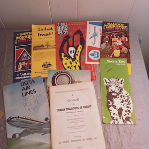 May include: A collection of vintage travel brochures and maps, including a Delta Air Lines route map, a guide to the Jardin Zoologique de Quebec, and a brochure for the Bronx Zoo. Other brochures include "See Amish Farmlands!" and "Santa's Workshop North Pole NY."