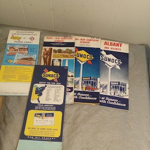 May include: A collection of vintage Sunoco travel brochures and a travel card. The brochures feature state maps and gas station imagery. The text includes "Sunoco" and "Travel Card".