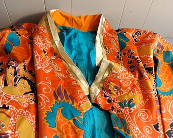 May include: A long-sleeved robe with a colorful paisley print in shades of orange, teal, yellow, and black. The robe has a mandarin collar with a gold trim and a teal lining.