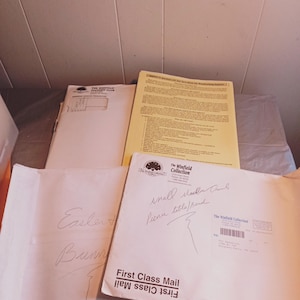 May include: A white envelope with the text "First Class Mail" written twice, once in black and once in blue. The envelope has handwritten text that says "Easter Bunny" and "small wooden trunk, picnic table/bench".