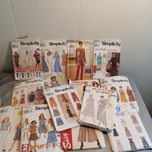 Peut inclure: Plusieurs patrons de couture Simplicity, présentant des modèles de robes, de séparations et de vêtements pour enfants. Les pochettes affichent des images des vêtements finis et comprennent du texte tel que "It's So Easy" et "2 Hour Basic".