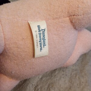 May include: A light pink plush toy with a tag that reads "Disneyland Walt Disney World &copy; 1984 DISNEY."