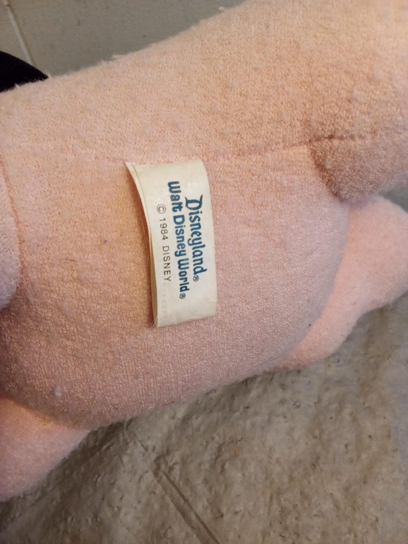 May include: A light pink plush toy with a tag that reads "Disneyland Walt Disney World &copy; 1984 DISNEY."