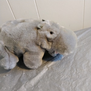 Könnte beinhalten: Ein graues Plüsch-Nilpferd-Spielzeug mit weicher, flauschiger Textur. Das Spielzeug liegt auf der Seite mit dem Kopf zur Seite gedreht.