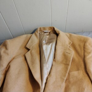 May include: A tan blazer with a satin lining. The blazer has a single button closure and two pockets.