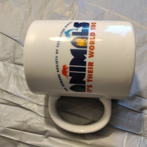May include: White ceramic mug with a blue and orange graphic that says "Animals It's Their World Too" and the logo for The Humane Society of the United States.