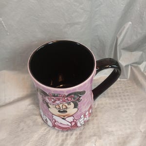Puede incluir: Taza de cer&aacute;mica con Minnie Mouse. La taza tiene interior y asa negros, con exterior rosa decorado con un gr&aacute;fico de Minnie Mouse y lunares. La taza mide aproximadamente 10 cm de alto.