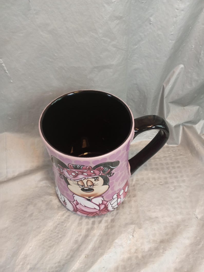Puede incluir: Taza de cer&aacute;mica con Minnie Mouse. La taza tiene interior y asa negros, con exterior rosa decorado con un gr&aacute;fico de Minnie Mouse y lunares. La taza mide aproximadamente 10 cm de alto.