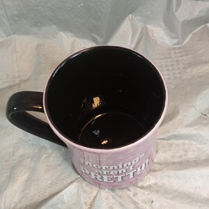 Puede incluir: Una taza de caf&eacute; de cer&aacute;mica con interior y asa negros. El exterior es de color lila claro con las palabras "mornings aren't PRETTY!" impresas en blanco. La taza est&aacute; sobre una superficie blanca arrugada.