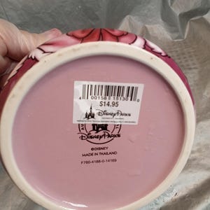 Puede incluir: Un cuenco rosa de cer&aacute;mica de Disney Parks con borde blanco y dise&ntilde;o floral. La parte inferior del cuenco tiene un interior rosa y una pegatina de Disney Parks. Hecho en Tailandia.